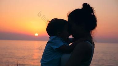 一个孩子和他妈妈在日落时拥抱和亲吻